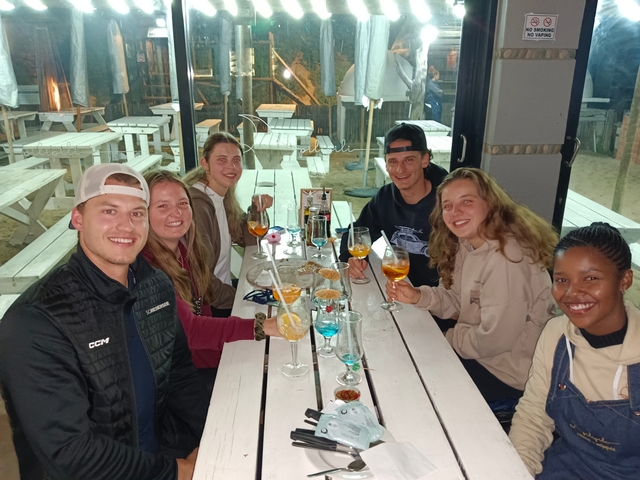 A group of friends having drinks at a picnic table indoors.