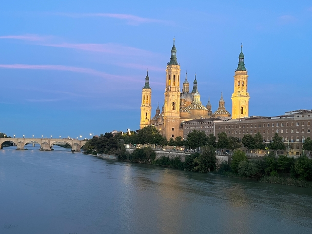Illuminated basilica by the river in the evening.