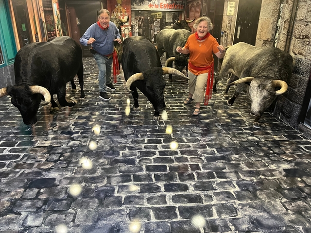People posing with bulls on a cobblestone street.
