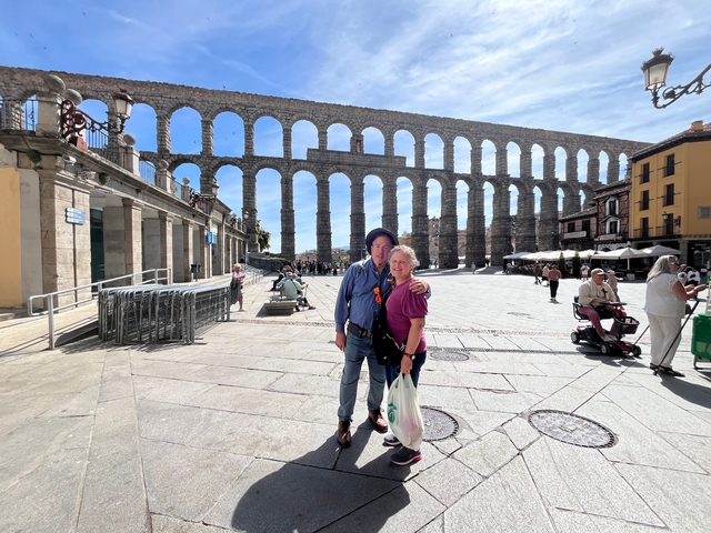 Couple posing in front of an ancient aqueduct.