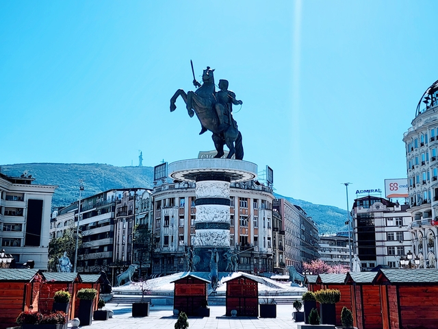 Equestrian statue in the center of a bustling city square.