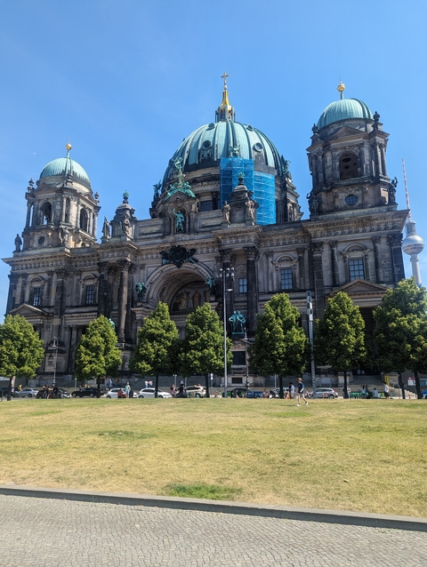 Large historic church with trees and a TV tower in the background.