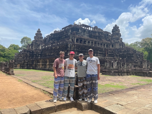 Four people posing in front of a historical temple ruin.