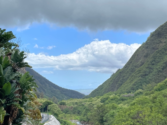 Mountain valley with expansive blue sky and clouds.