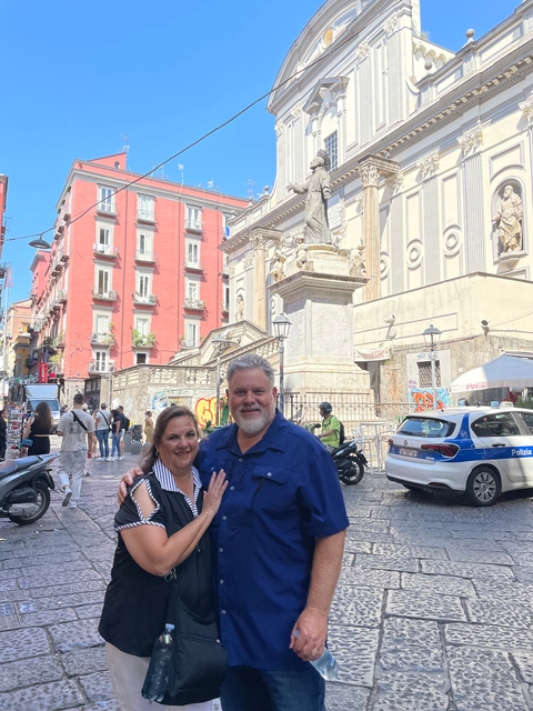 A couple posing in front of historic buildings in a city center.