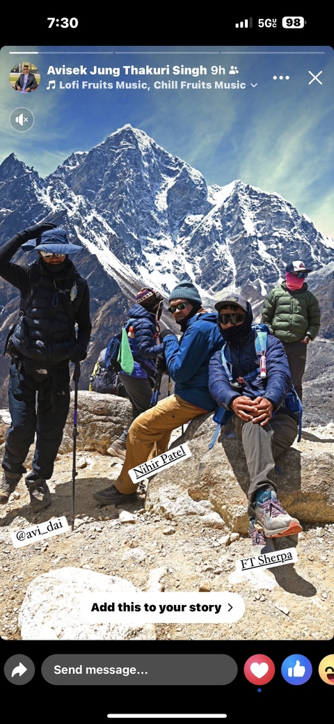 Group of hikers resting on a rocky terrain with snow-capped mountains.