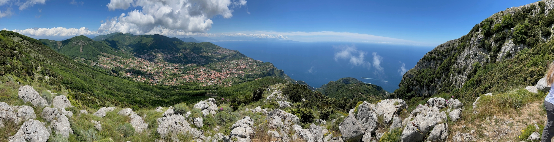Panoramic view of mountains and a distant coastline with a cloudy sky.