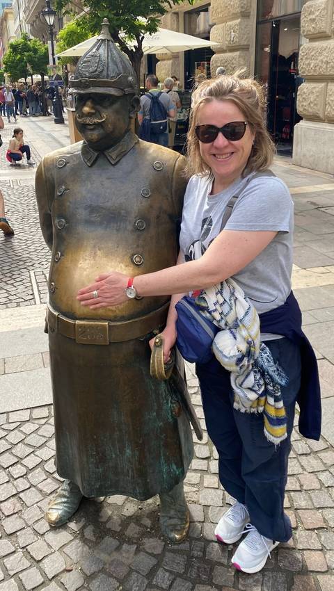 Person touching a shiny statue in a public area.