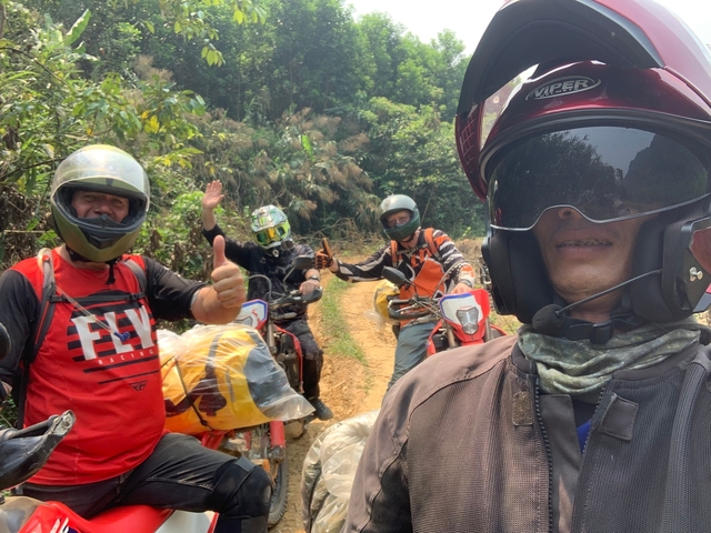 Group of motorcyclists giving thumbs up on a trail.