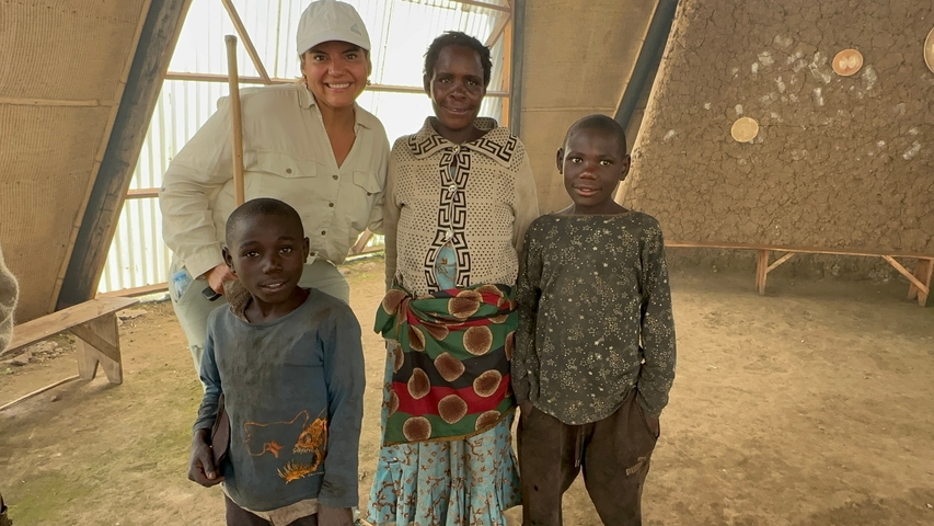Four people posing inside a traditional hut.