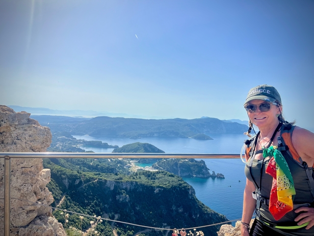 Woman posing with a coastal view of mountains in the background.