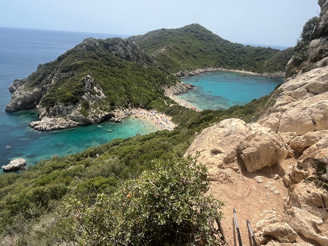 Aerial view of a cove with a beach surrounded by lush greenery.
