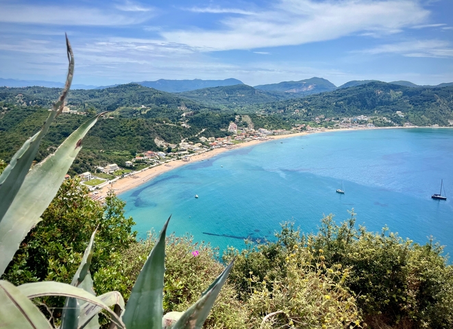 Panoramic view of a coastal town with blue waters and hills.