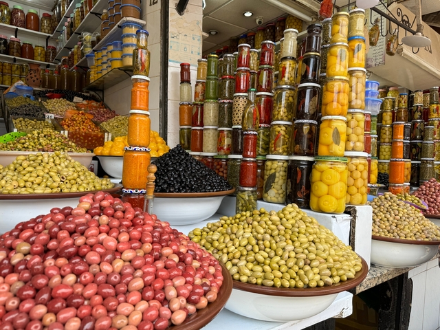 Market stand with various jars and bowls of olives and pickles.