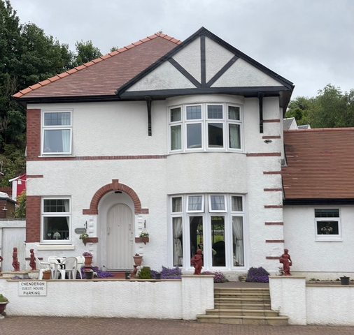 A two-story white house with red brick trim and a bay window.