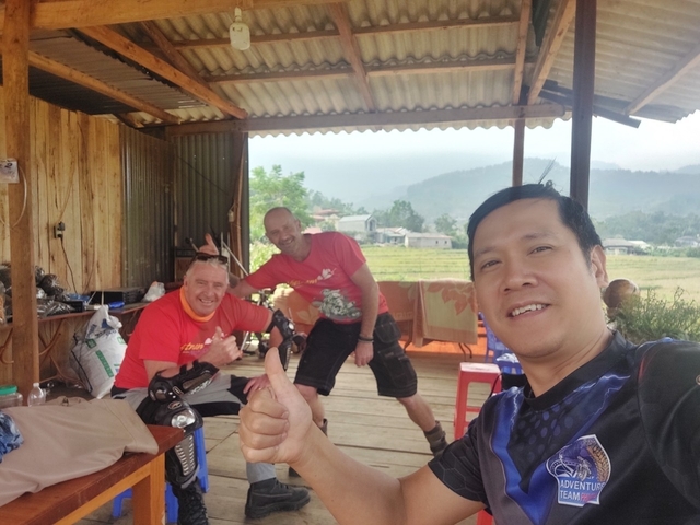 Three men indoors, one giving a thumbs up.