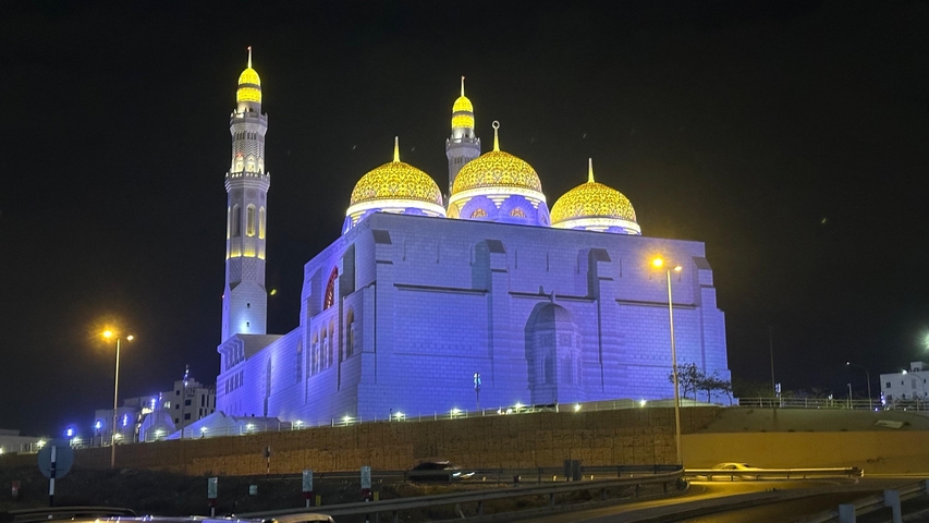 Illuminated mosque with multiple domes at night.