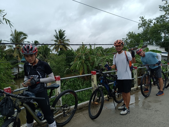 Cyclists posing on a bridge over a river.