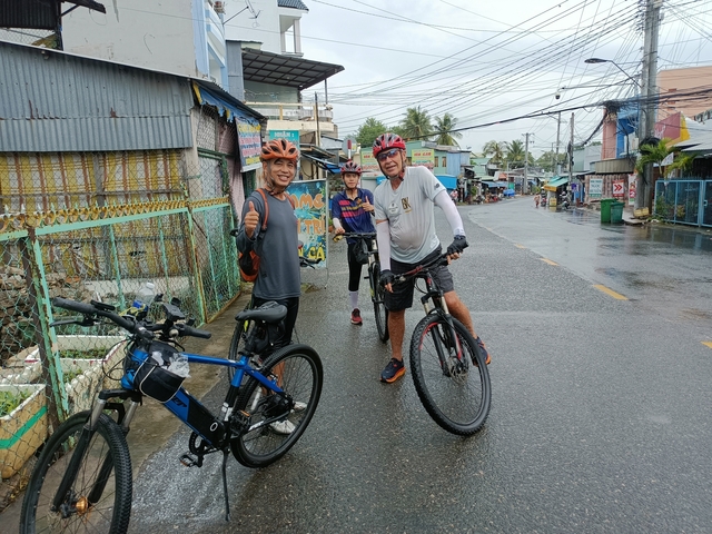 Cyclists posing on a street in an urban area.