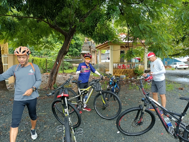 Group of cyclists with bicycles near a building.