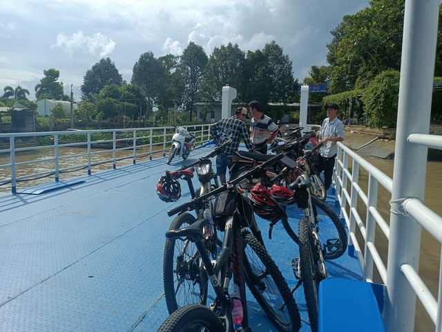People and bikes on a ferry crossing a river.