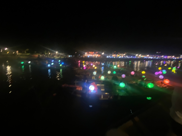 Blurry image of lit lanterns floating on water at night.
