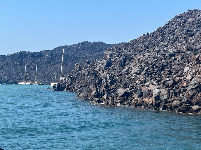 Rocky coastline with sailboats in the water.