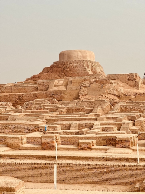 Ancient stepped structures with a large dome in the background.