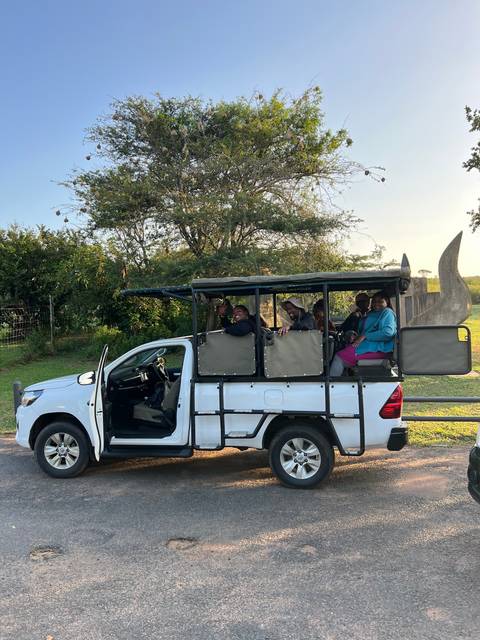 Group of people on a safari vehicle waving.