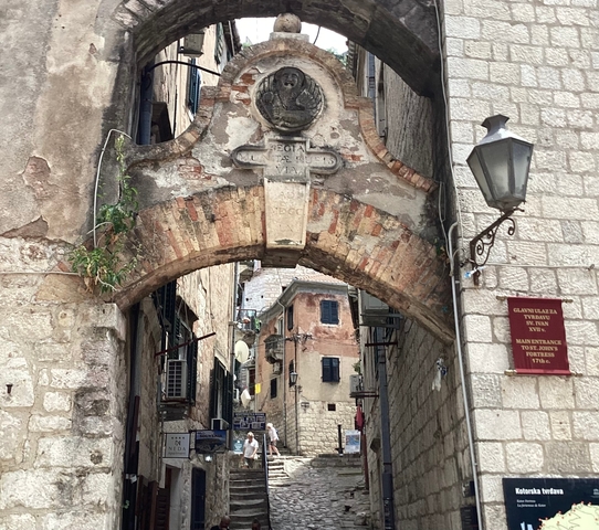 Historic stone archway in a narrow street with a lantern and building facades.