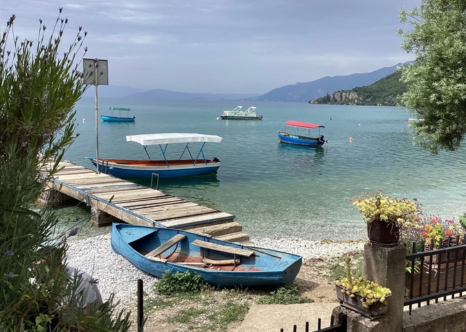 Lake with blue boats, a dock, and mountains in the background.
