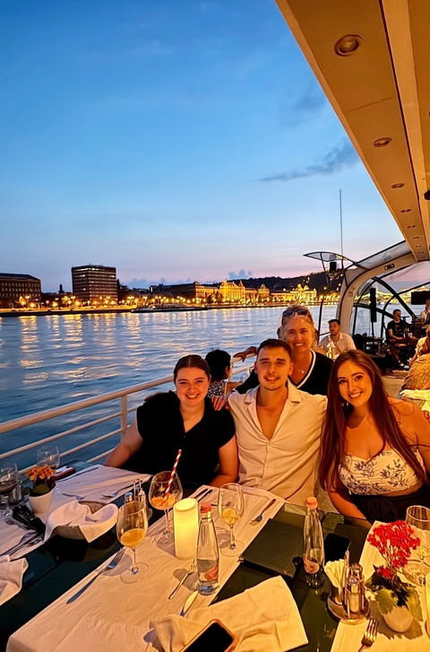 People enjoying a river cruise at sunset with city skyline.