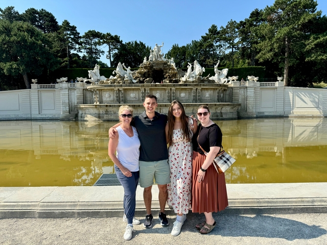 People posing in front of a decorative fountain with sculptures.