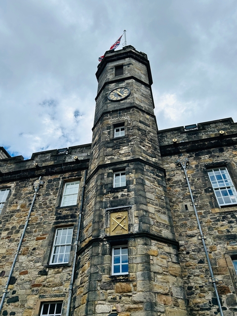 Stone building with a clock tower, surrounded by clouds.