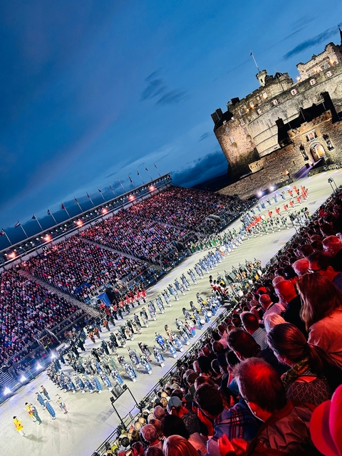 Nighttime military parade at a large stadium.