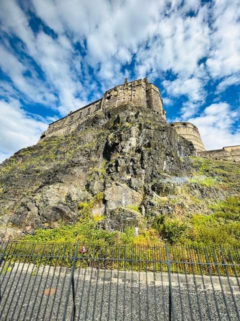 Castle atop a rocky hill with a blue sky.