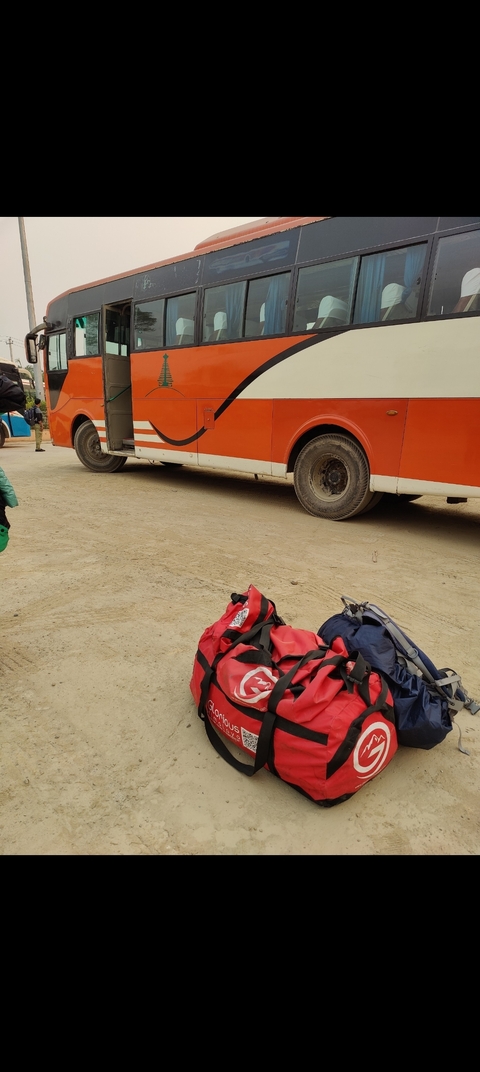 Travel bags and a bus on a dirt road.