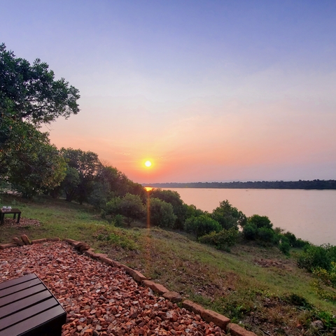 Sunset view over a river with trees in the foreground.