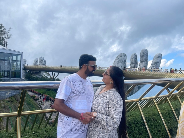 Couple posing on a bridge with giant stone hands.