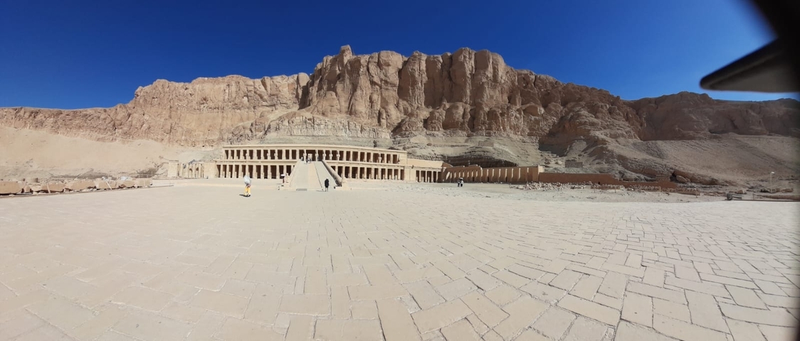 A wide view of an ancient Egyptian temple with tourists walking around.