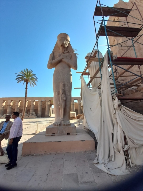 A large statue with a person and a palm tree in the background.
