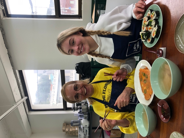 Two women sitting at a table with various dishes in front of them.