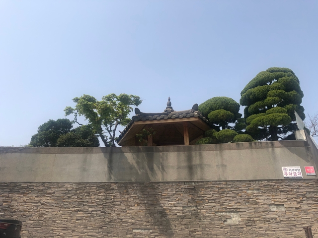 A traditional pagoda roof with neatly trimmed trees nearby.