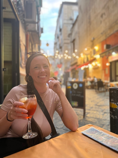 Woman enjoying a drink on a bustling evening street.