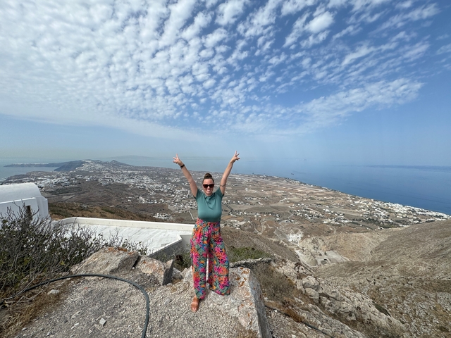 Woman posing on a hilltop with a wide sea view.