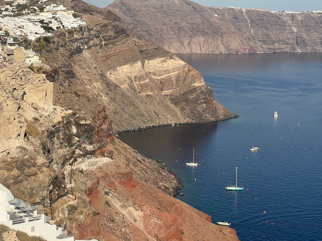 Scenic view of a coastline with boats and steep cliffs.