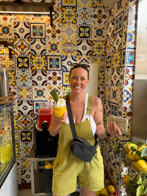 Woman smiling while holding ice cream in front of a decorated wall.
