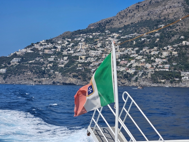 Flag on a boat with a coastal view.