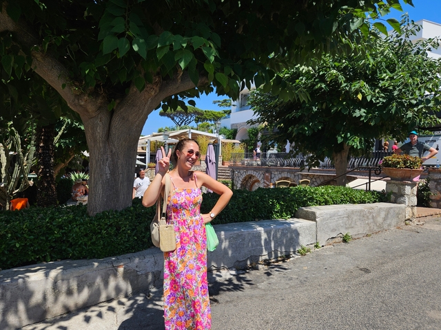 Woman posing under a tree in a sunny area.