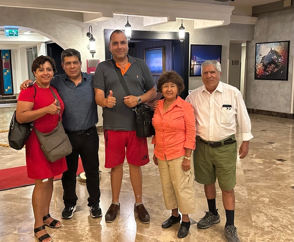 Group of people posing inside a building with artworks on the walls.